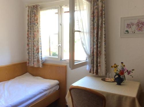 a room with two beds and a window with a table at Haus Seefrieden in Uhldingen-Mühlhofen