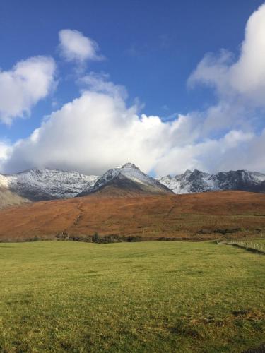 a field with snow capped mountains in the background at Tyndrum Lodges in Tyndrum