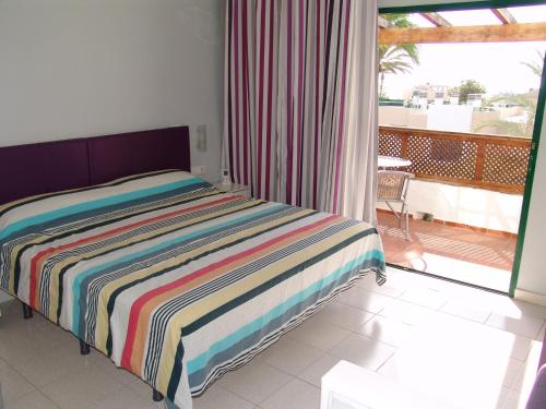 1 dormitorio con 1 cama con una manta a rayas de colores en Moderno apartamento con vistas al mar, en Playa del Águila