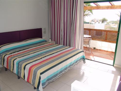 sypialnia z łóżkiem z kolorowym kocem w paski w obiekcie Moderno apartamento con vistas al mar w mieście Playa del Aguila