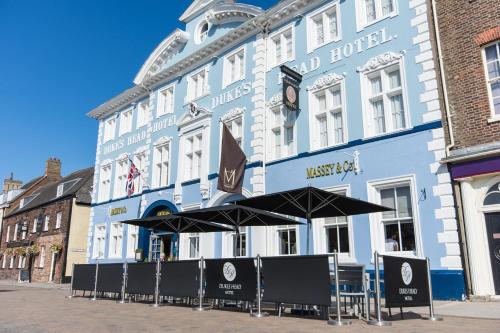 a large blue building with umbrellas in front of it at Dukes Head Hotel in King's Lynn