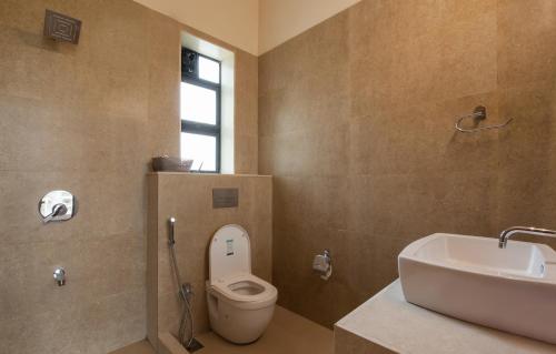 a bathroom with a white toilet and a sink at StayVista's Greenwoods Villa 1 - City-Center Villa with Private Pool, Terrace, Lift & Carrom Board in Lonavala