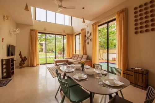 a living room with a table and chairs at StayVista's Greenwoods Villa 1 - City-Center Villa with Private Pool, Terrace, Lift & Carrom Board in Lonavala
