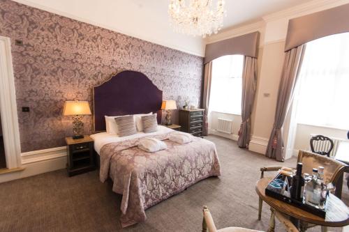 a bedroom with a large bed and a chandelier at Dukes Head Hotel Kings Lynn in Kings Lynn