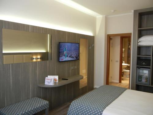 a hotel room with a bed and a tv on the wall at Delle Nazioni Milan Hotel in Milan