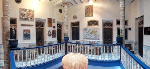 a lobby with a blue railing and paintings on the walls at The Chill Art Hostel in Essaouira