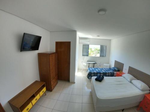 um quarto com um sofá, uma cama e uma televisão em Pousada Costa da Riviera em Bertioga
