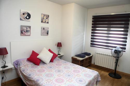 ラス・ナバス・デル・マルケスにあるApartamento Castillaのベッドルーム1室(赤い枕のベッド1台、窓付)