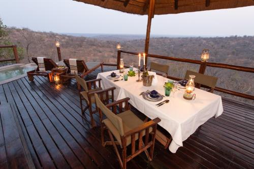 a dining table on a deck with a view at Parsons Hilltop Safari Camp in Balule Game Reserve