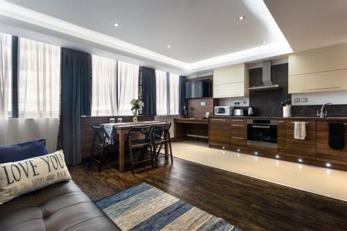 a living room with a couch and a kitchen at Livin' Serviced Apartments in Watford