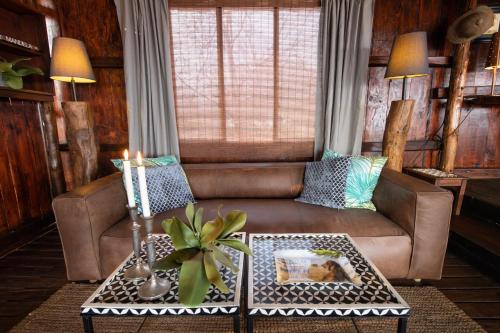 a living room with a brown couch and a table at Parsons Hilltop Safari Camp in Balule Game Reserve