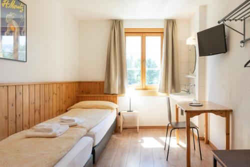 a hotel room with two beds and a desk at Hostel by Randolins in St. Moritz