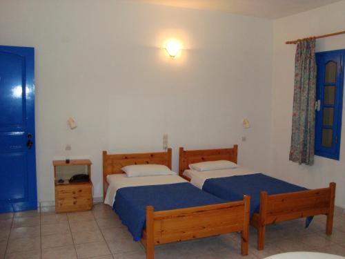 a bedroom with two beds with blue sheets at Creta Sun Hotel Studios in Agia Pelagia