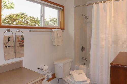 a white bathroom with a toilet and a window at 9 Condo in Lopez