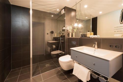a bathroom with a sink and a toilet and a shower at Timehouse Serviced Apartments in Munich