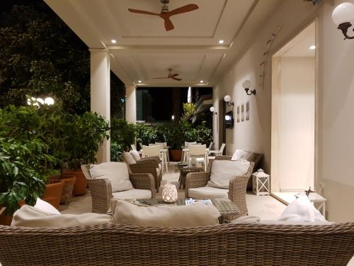 a patio with wicker chairs and tables and a ceiling at Hotel La Primula in Forte dei Marmi