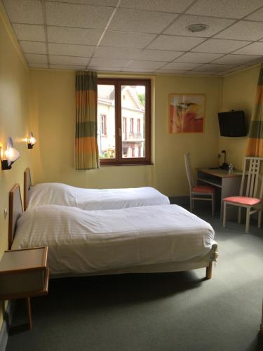 a bedroom with two beds and a desk and a window at Hostellerie d'Alsace in Cernay