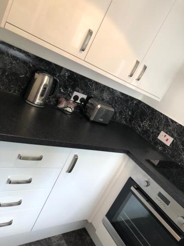 a kitchen with white cabinets and a black counter top at Number Fifty Six in Hawick