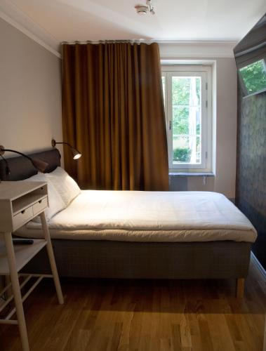 a bedroom with a bed and a desk and a window at Södra Hotellet in Norrköping