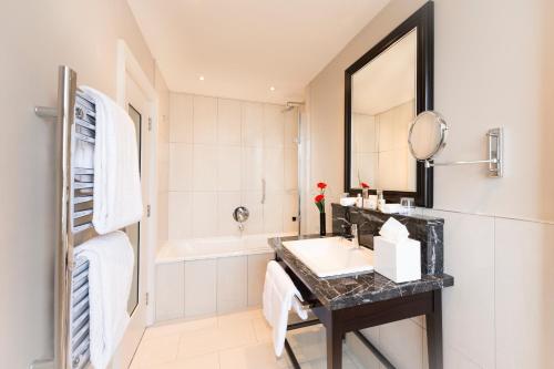 a bathroom with a sink and a tub at The Bailey's Hotel London Kensington in London