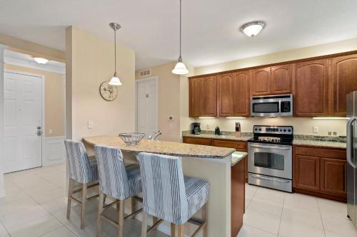 eine Küche mit Holzschränken und eine Kücheninsel mit Barhockern in der Unterkunft Orlando Resort Rentals at Universal Boulevard in Orlando