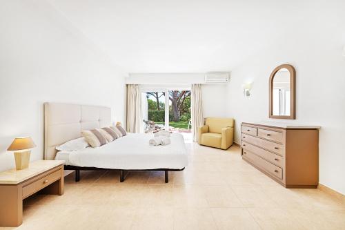 a white bedroom with a bed and a mirror at Victory Village 9F in Quinta do Lago