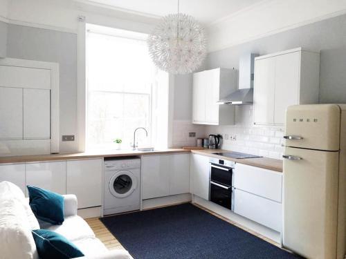 a kitchen with white cabinets and a washer and dryer at Stylish City Centre Apartments - D Terrace Residence in Edinburgh