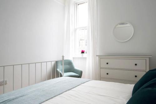 a bedroom with a bed and a chair and a window at Stylish City Centre Apartments - D Terrace Residence in Edinburgh