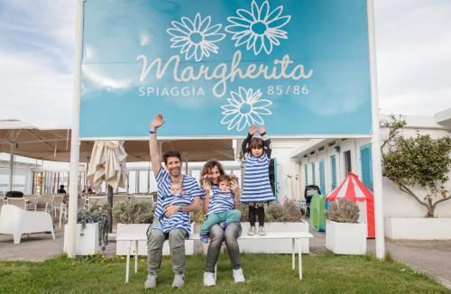 a man and two children sitting under a sign at Hotel Riziana in Cervia