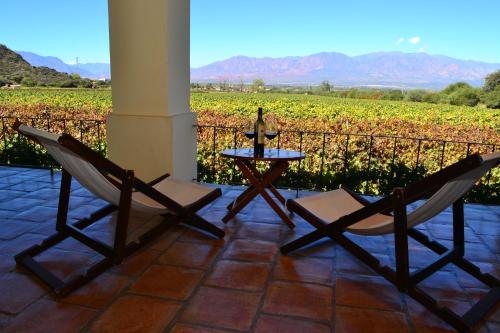 a patio with two chairs and a table with a bottle of wine at Viñas De Cafayate Wine Resort in Cafayate