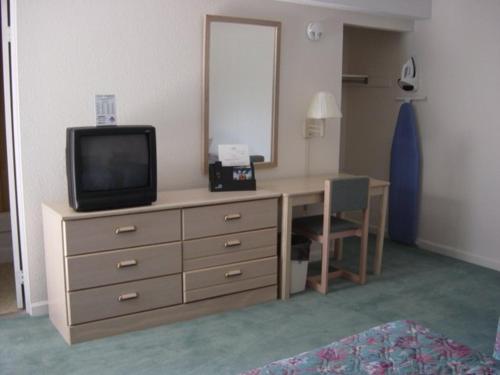 a room with a desk with a television on a dresser at Prestige Inn in Lafayette