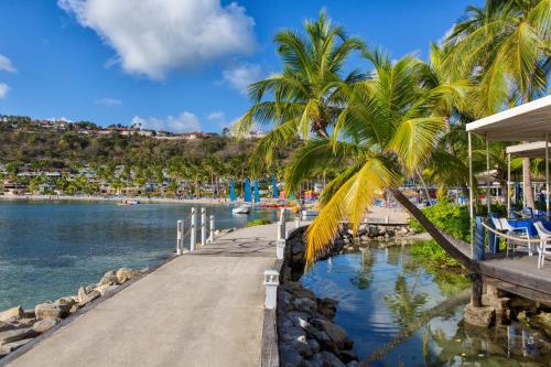 a dock with palm trees next to a body of water at St. James's Club Resort - All Inclusive in English Harbour Town