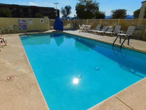 a large blue swimming pool with chairs and a table at Island Suites in Lake Havasu City