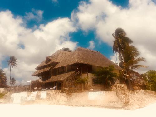 una casa con techo de paja en una playa en Vanilla House, en Jambiani