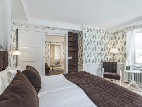 a bedroom with a large bed and a chair at Åkerblads Hotell Gästgiveri Spa in Tällberg