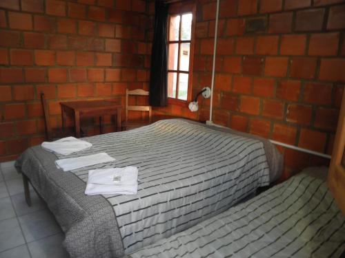 1 dormitorio con cama y pared de ladrillo en Alojamiento Termal Guaviyú, en Termas de Guaviyú