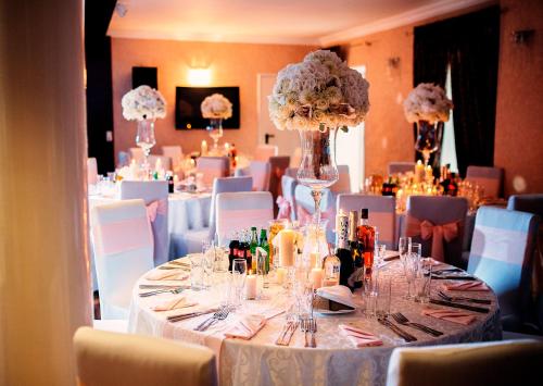 a table set up for a wedding with flowers and candles at Hotel Tomas in Šiauliai