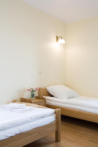 two beds in a room with white walls and wooden floors at Dworek Zyskowskiego in Danowskie