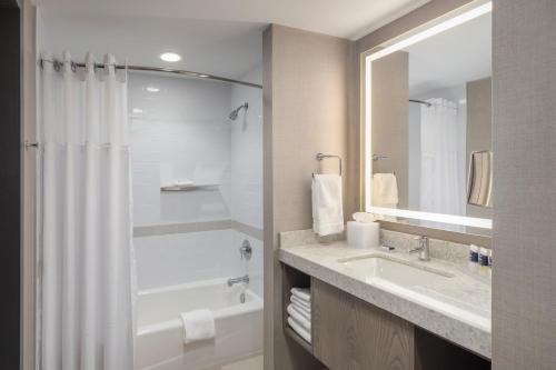a bathroom with a tub and a sink and a mirror at The Summit Hotel in Cincinnati