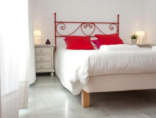 una camera da letto con un grande letto bianco con cuscini rossi di Archeros Skyview by Valcambre a Siviglia