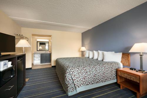 a hotel room with a bed and a flat screen tv at Days Inn by Wyndham Clearwater/Central in Clearwater