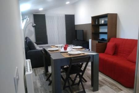 un salon avec une table et un canapé rouge dans l'établissement Très confortable studio maison au pied dufaron, à Toulon