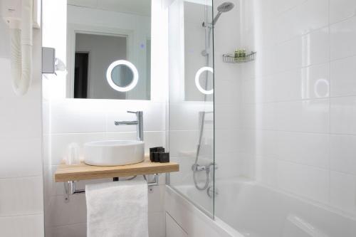 a white bathroom with a sink and a mirror at H&ocirc;tel Moulin Vert in Paris