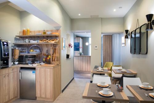 une cuisine et une salle à manger avec tables et chaises dans l'établissement Hôtel Moulin Vert, à Paris