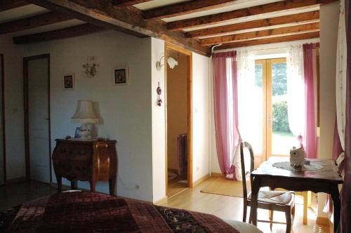 Schlafzimmer mit einem Bett, einem Tisch und einem Fenster in der Unterkunft Chambres d'hôtes La Hulotte 69 in Villechenève