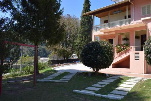 a house with a tree in front of a driveway at Pousada Sino dos Ventos in Campos do Jordão