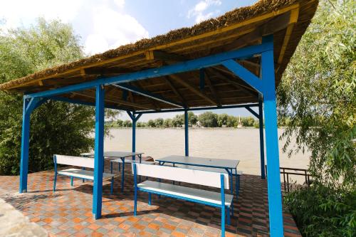 a picnic table and benches under a pavilion next to a river at Stuffino Crisan in Crisan