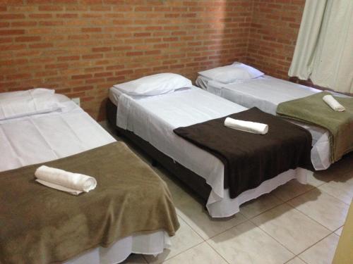 three beds in a room with a brick wall at Aconchego do Guara , próximo ao centro médico, Boldrini, Unicamp, Laboratório CNPEN, Universidades e Hospital Sobrapar in Barão de Geraldo