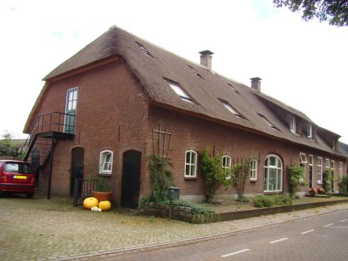 a large red brick building with a gambrel roof at B&B Onder Ons Riet in Cromvoirt