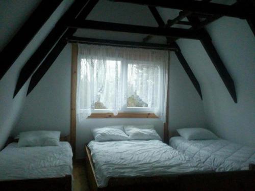 two beds in a room with a window at Domek Zalesie in Barczewo